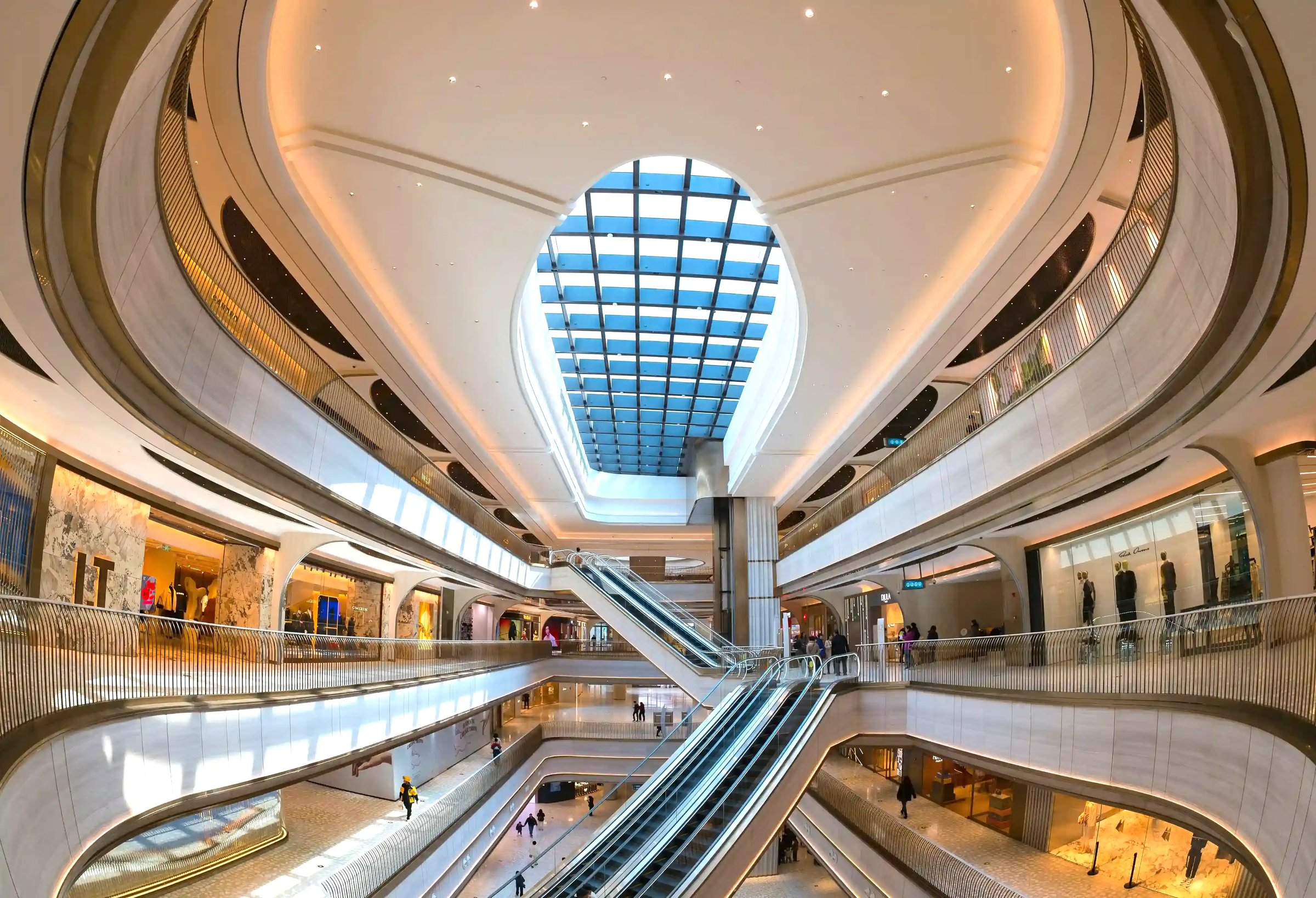Modern multi-level luxury shopping mall with escalators, skylight ceiling, and premium brand boutiques – ideal environment for high-end retail mystery shopping.
